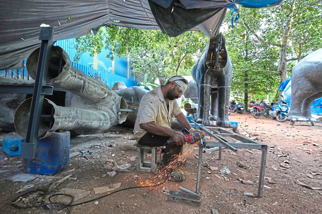 a worker welding parts to build a robotic elephant. -AP