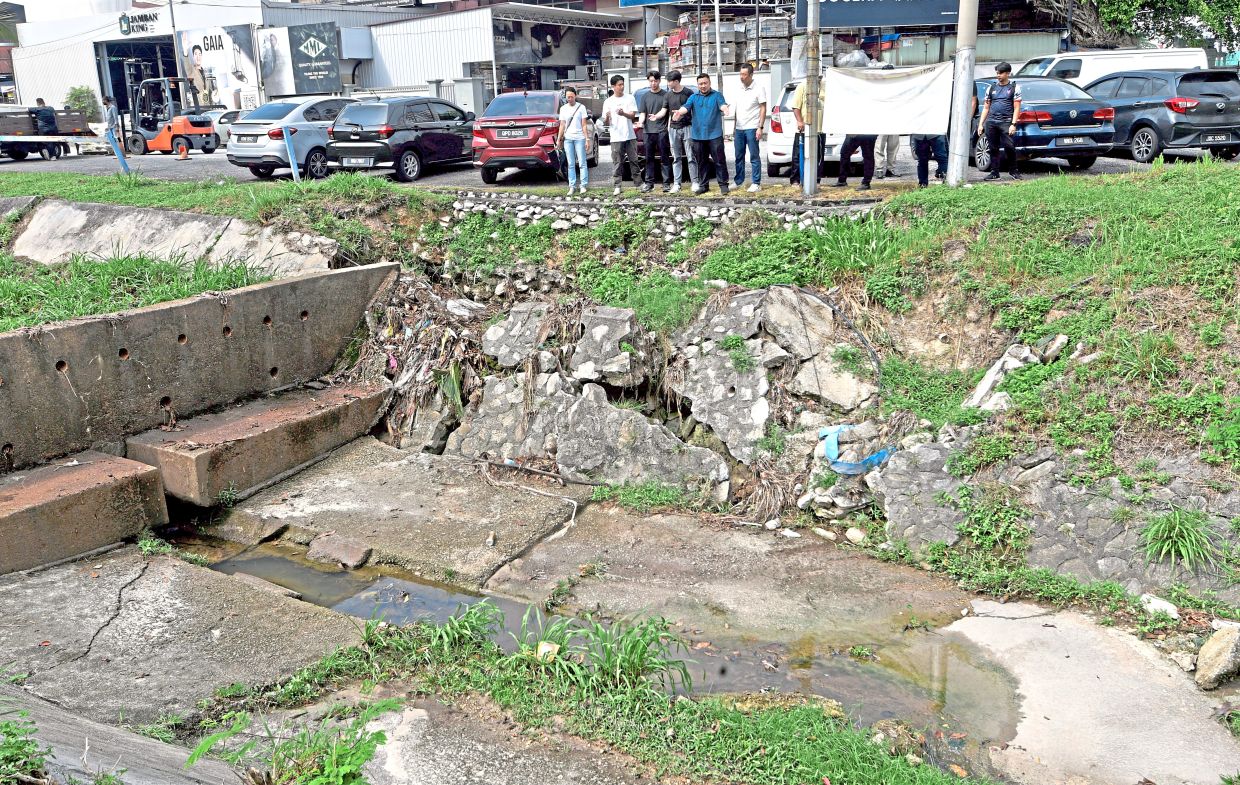 Residents highlighting the damaged culvert openings and accumulated debris at the drainage system along Jalan Layang-Layang 1. — AZHAR MAHFOF/The Star