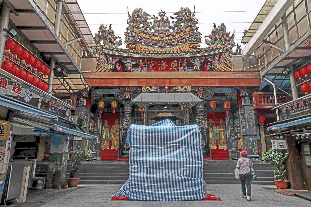 Safety precautions: Statues outside Dianji Temple are covered with protective tarpaulins in Keelung, Taiwan. — AFP