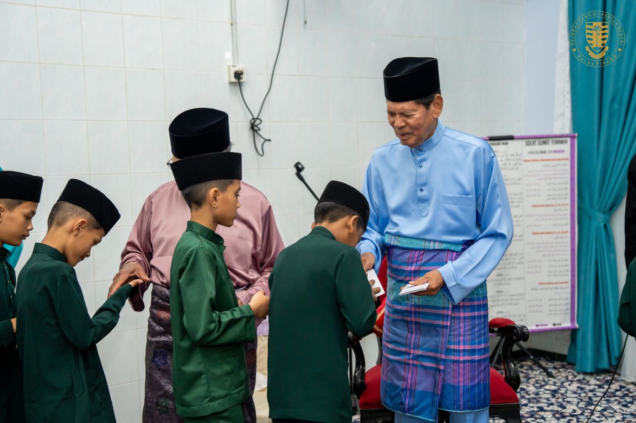 Ramli handing out duit raya to children at a Hari Raya gathering.