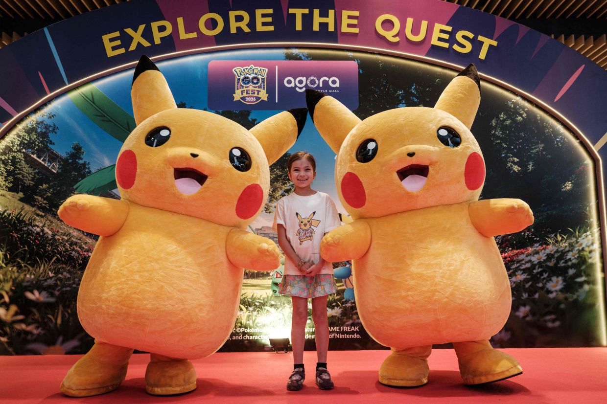 Two Pikachu mascots pose for a photograph with a girl during 'Pokemon GO Fest: Global', a worldwide event marking the 10th anniversary of Pokemon GO, an augmented reality mobile game, at Agora Mall in Jakarta on Saturday, July 11, 2026. -- Photo by YASUYOSHI CHIBA / AFP