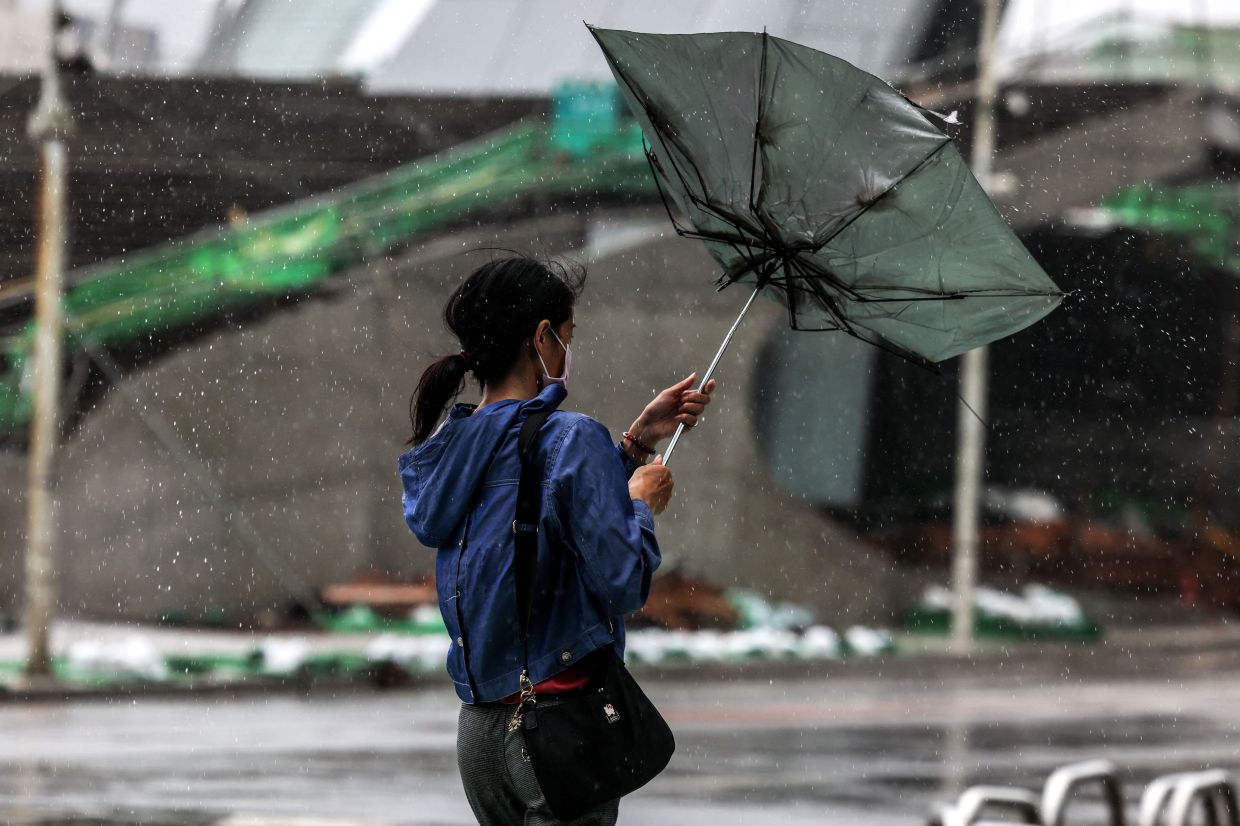 A woman struggles with an umbrella in strong winds and rain as Typhoon Bavi passes off northeastern Taiwan in Keelung on Saturday, July 11, 2026. More than 14,000 people in Taiwan have fled their homes, and many shops remain closed, as a typhoon pounding Japan's remote southwestern islands swept towards China on July 11. -- Photo by I-Hwa Cheng / AFP
