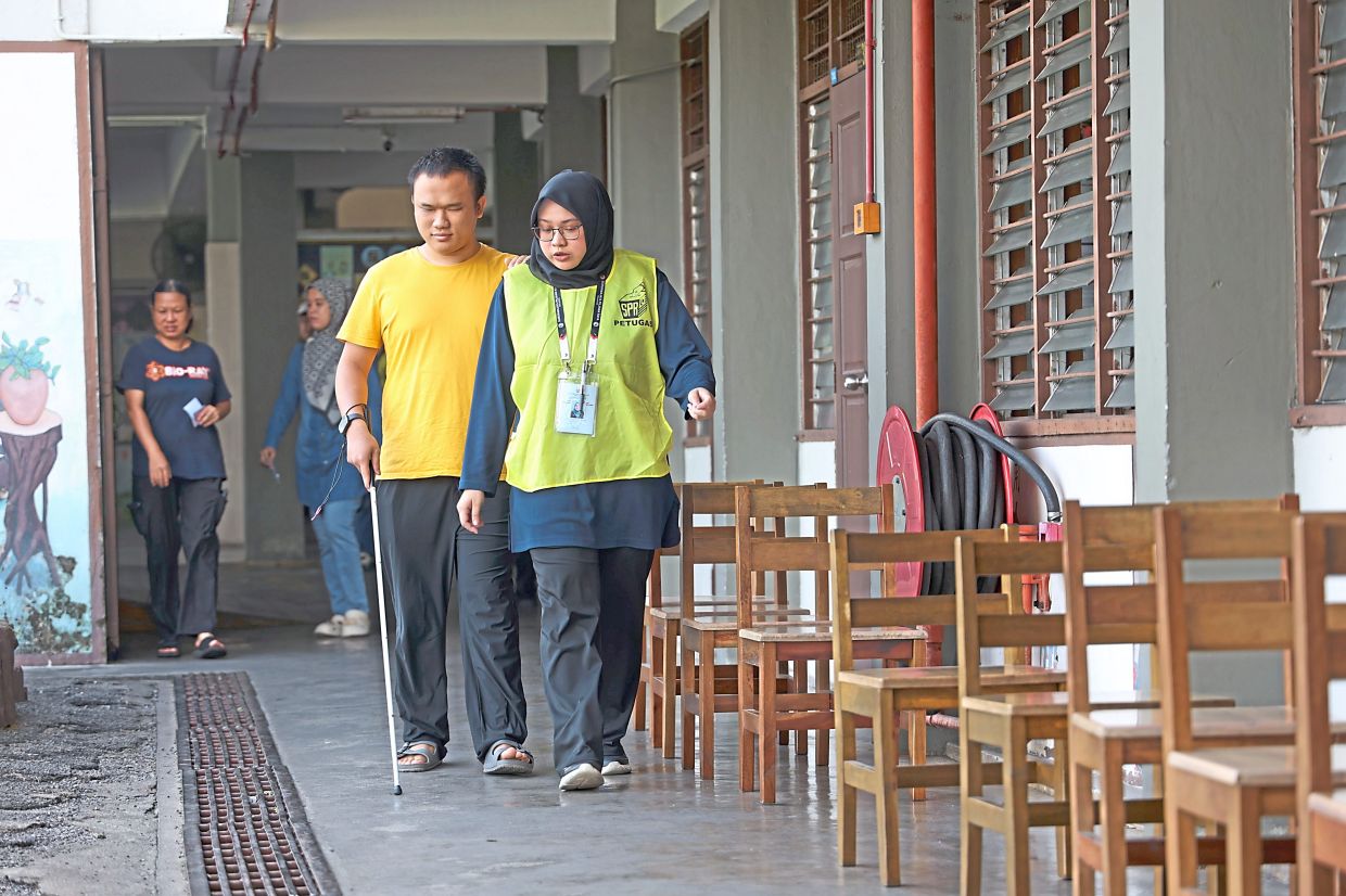 All set: Wong being guided to his polling stream at SJK (C) Tuan Poon in Simpang Renggam. — THOMAS YONG/The Star