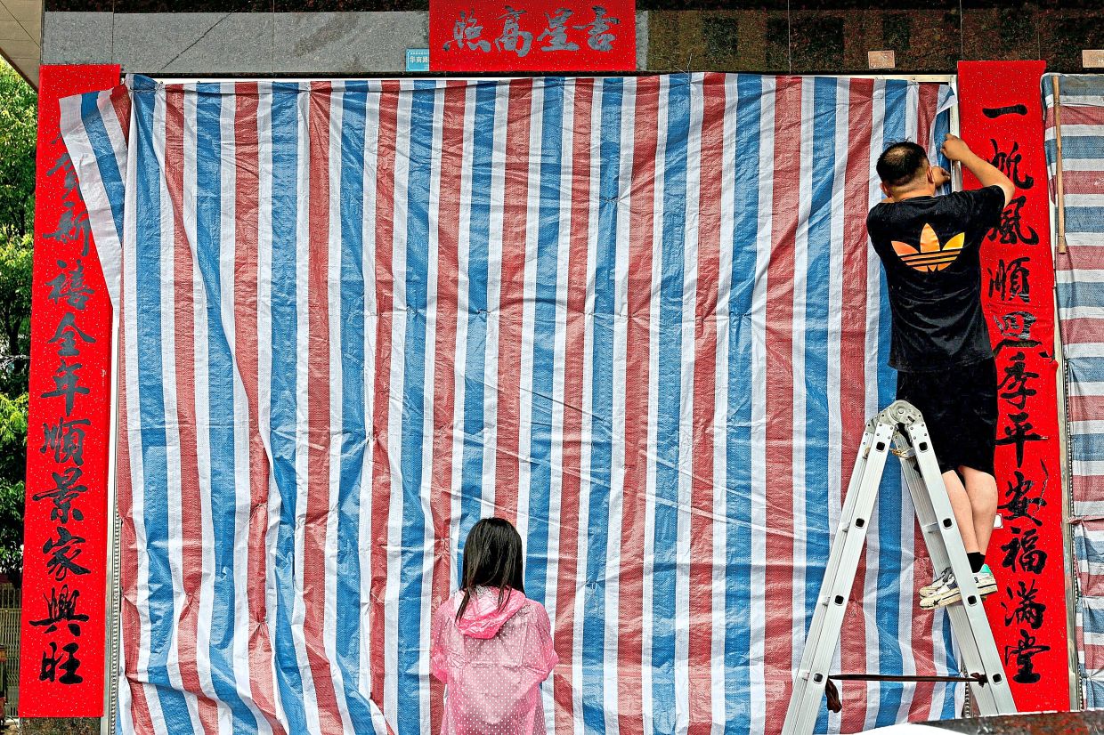 Storm shield: Locals installing a plastic sheet on a residential building ahead of the arrival of Typhoon Bavi in Wenzhou, Zhejiang province. — Reuters