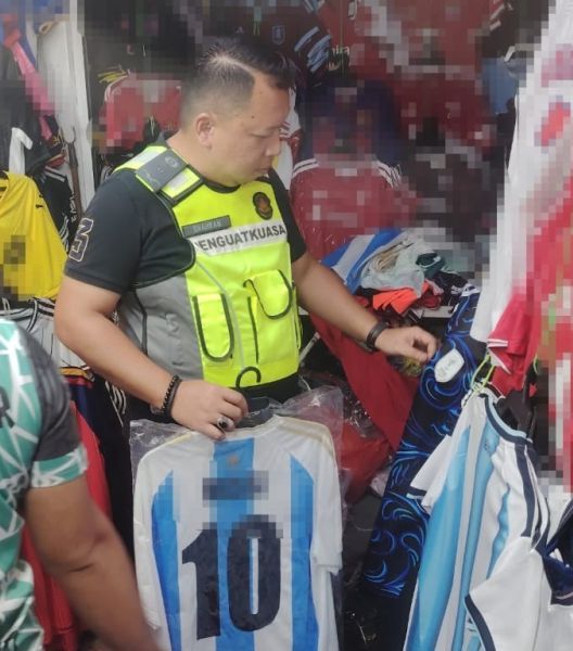 Penalty time: An enforcement officer raiding the counterfeit jersey shop along Jalan Petaling.