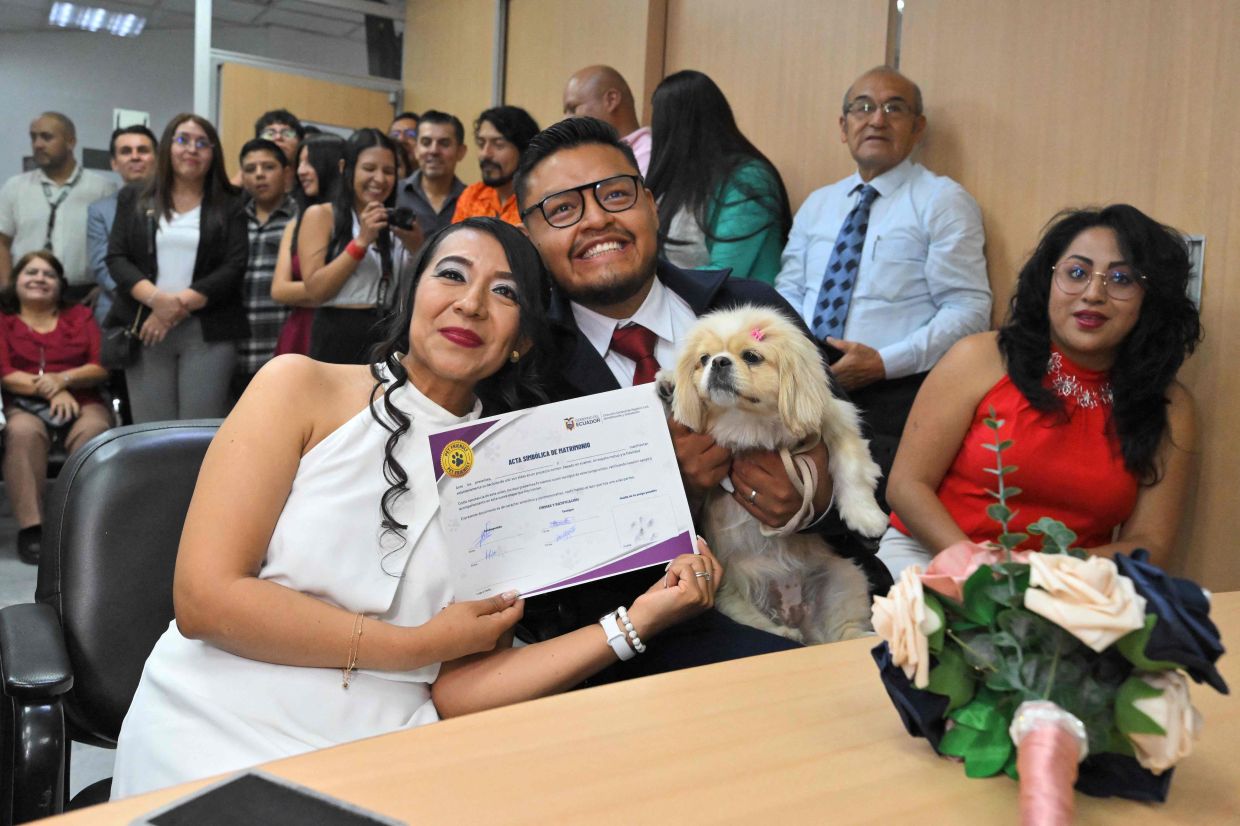 Andres Alquiga and Diana Tupiza with their pet Luna, show the symbolic marriage certificate with their pe's 'signature' after their wedding.