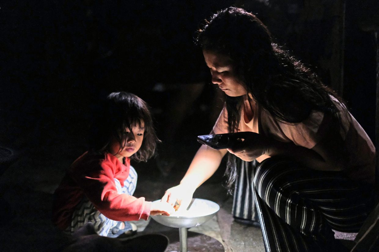 Atoshi Ayemi eats dinner with her daughter Azatina Murru inside their kitchen in Kohima.