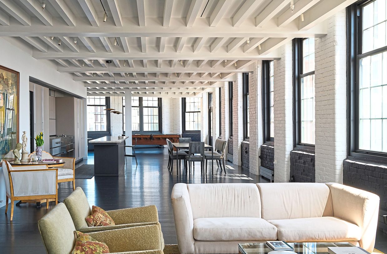 The loft's decor is a minimalist composition of black, white and grey, with ebonised wood floors and a white-painted beamed ceiling.