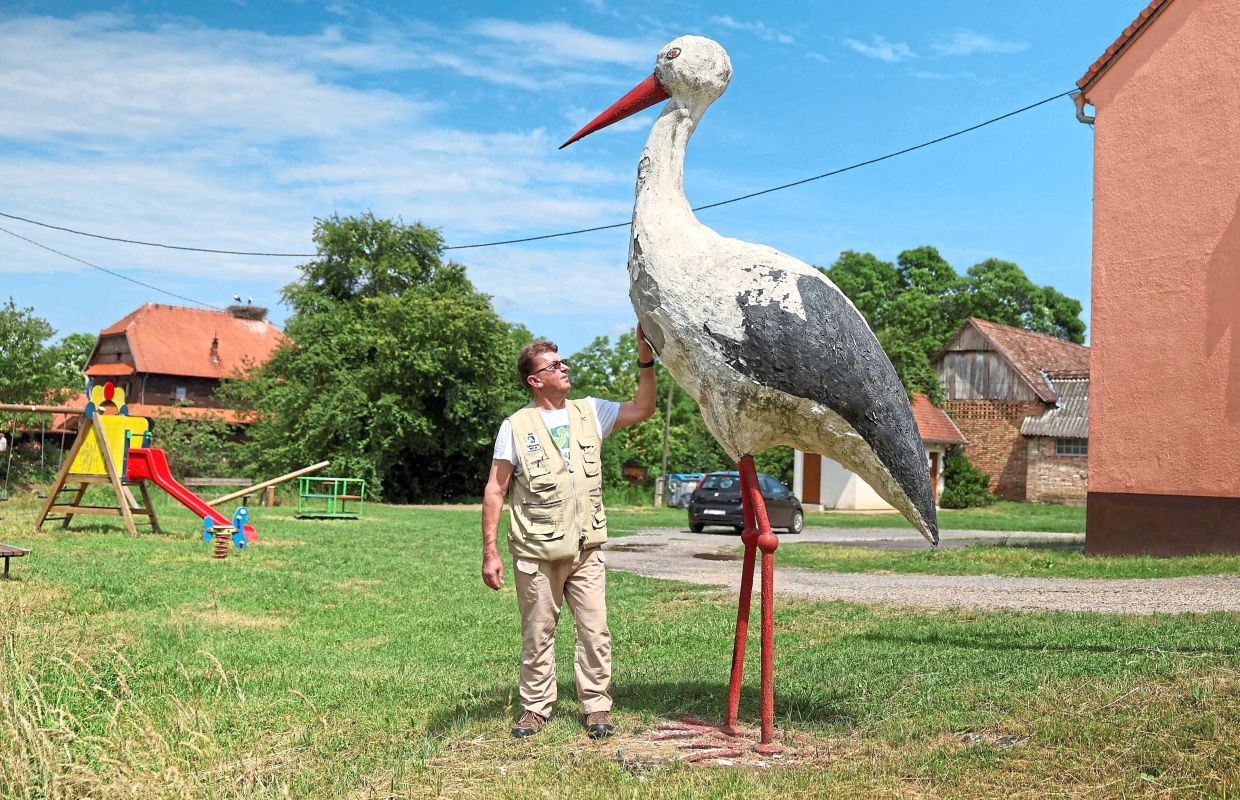 Anzil touches a wooden sculpture of a stork.