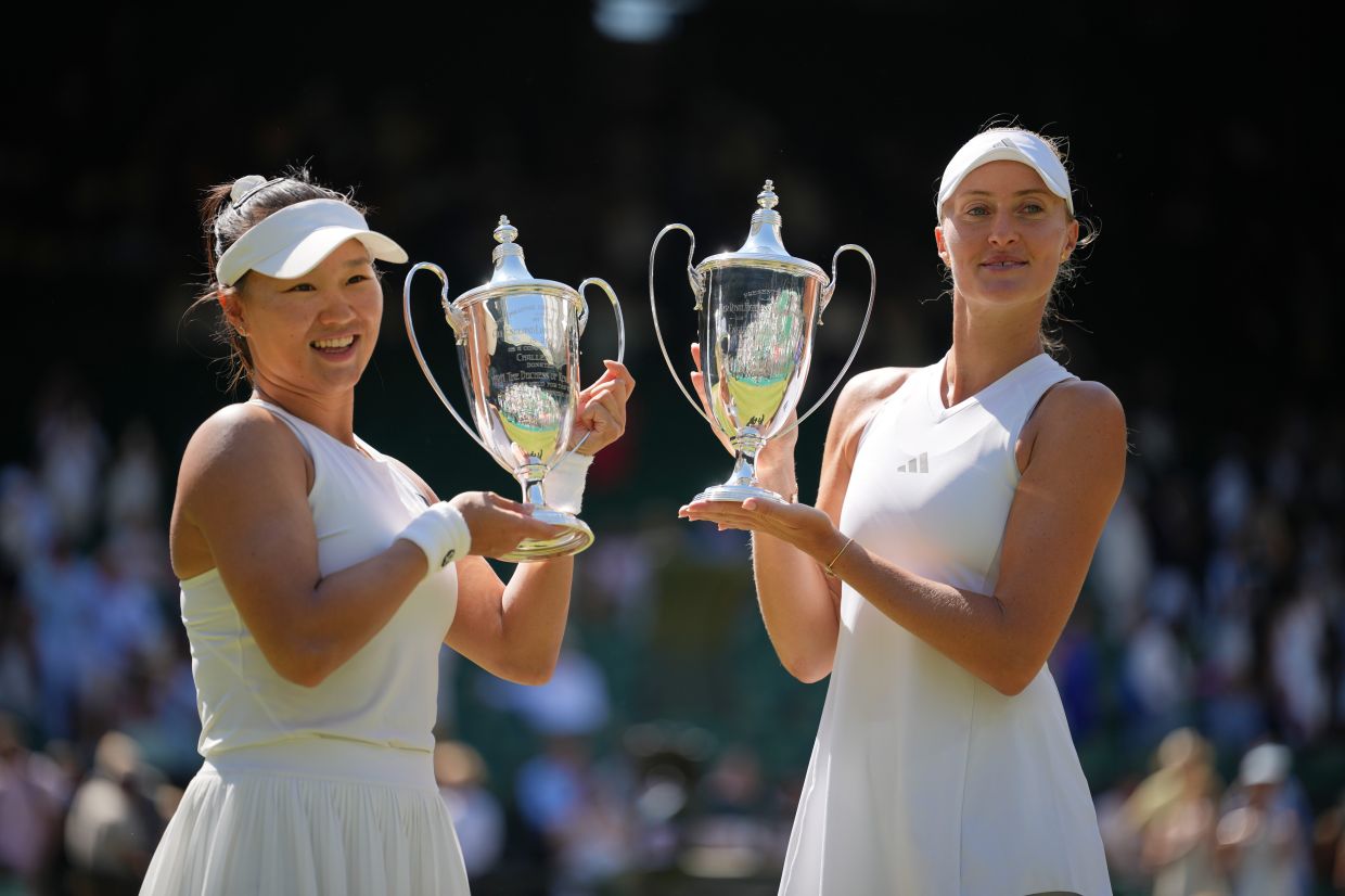 Kristina Mladenovic of France, right, and playing partner Hanyo Guo of China pose with the winners trophies after defeating Luisa Stefani of Brazil and Gabriela Dabrowski of Canada in the women's doubles final at the Wimbledon Tennis Championships in London, on Sunday, July 12, 2026. -- AP Photo/Kin Cheung