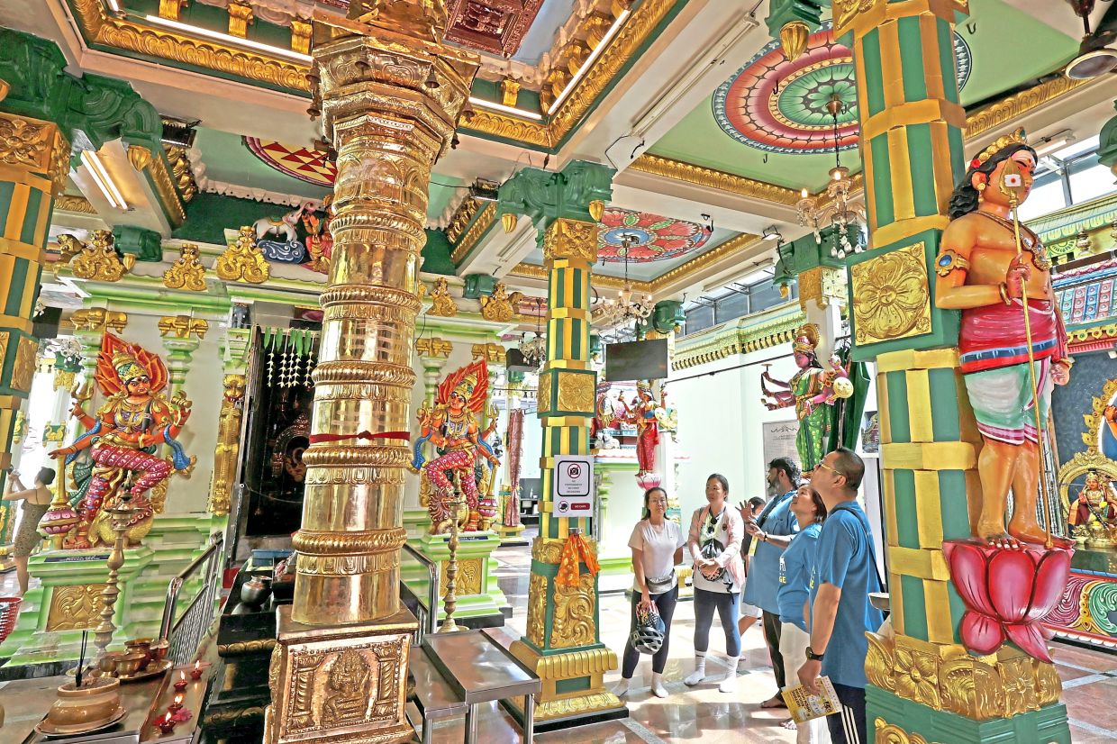 Visitors admiring the ornate ceiling and pillars while on a guided tour of Arulmigu Sri Maha Mariamman Temple at Lebuh Queen.