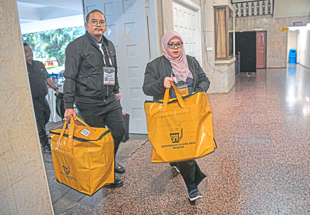 Election Commission officials carrying ballot boxes to the official counting centre for the Perling state seat at Dewan Jubli Intan, Johor Baru. — Bernama