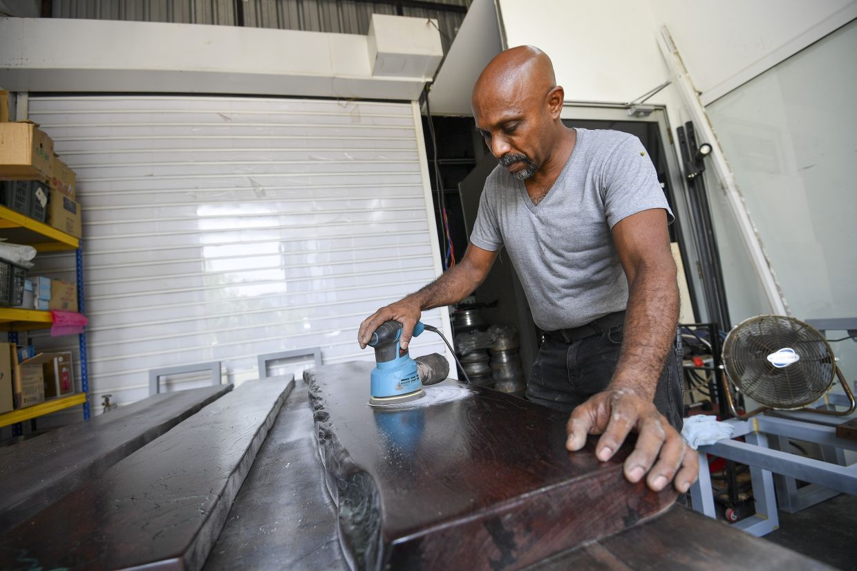 Adrian in his workshop polishing A dining table commissioned by a customer.