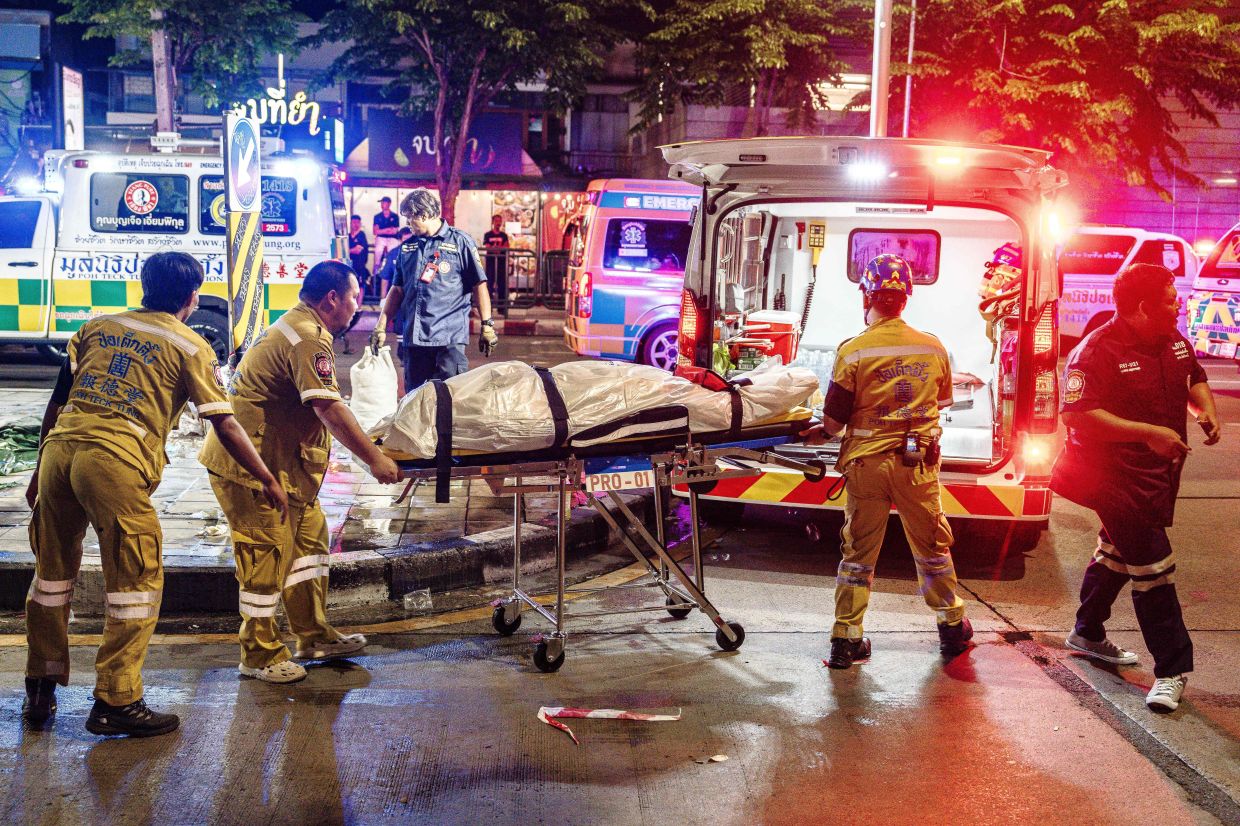 Emergency workers preparing to place the body of a victim into an ambulance after a fire at the Rong Beer Na Lat Phrao bar in Bangkok on July 13. - AFP
