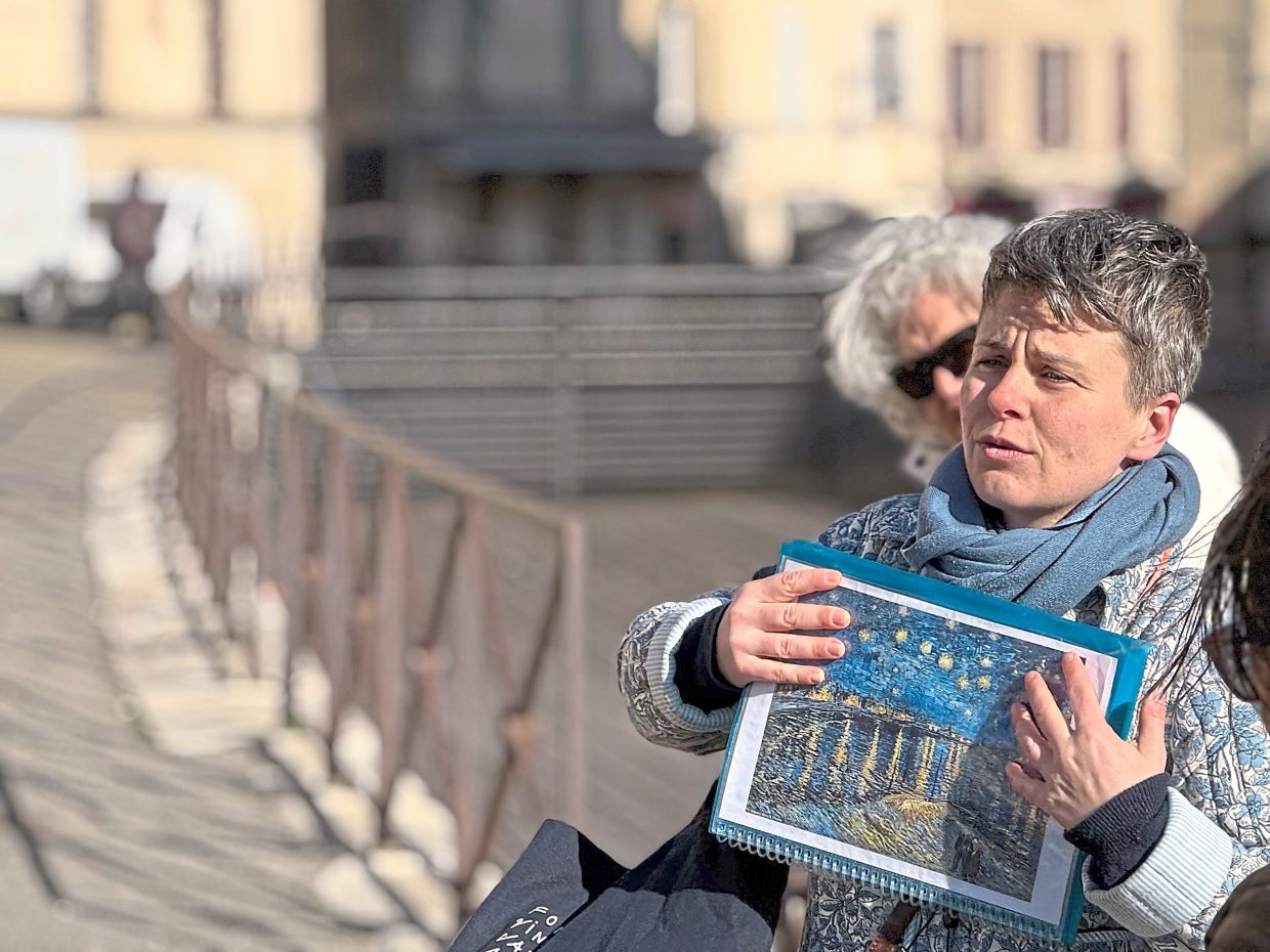 A tour guide showing a picture of van Gogh’s Starry Night Over The Rhone in Arles, where the artist spent a prolific part of his career.