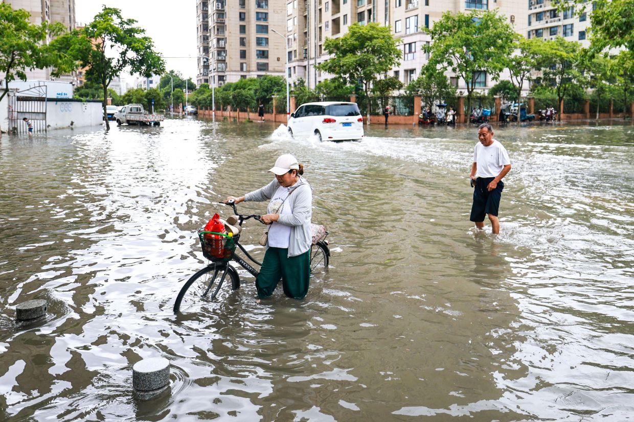 In this photo released by Xinhua News Agency, residents try to get through a flooded road in the aftermath of Typhoon Bavi in Yueqing City, in eastern China's Zhejiang Province. -- Photo: Jiang Han/Xinhua via AP
