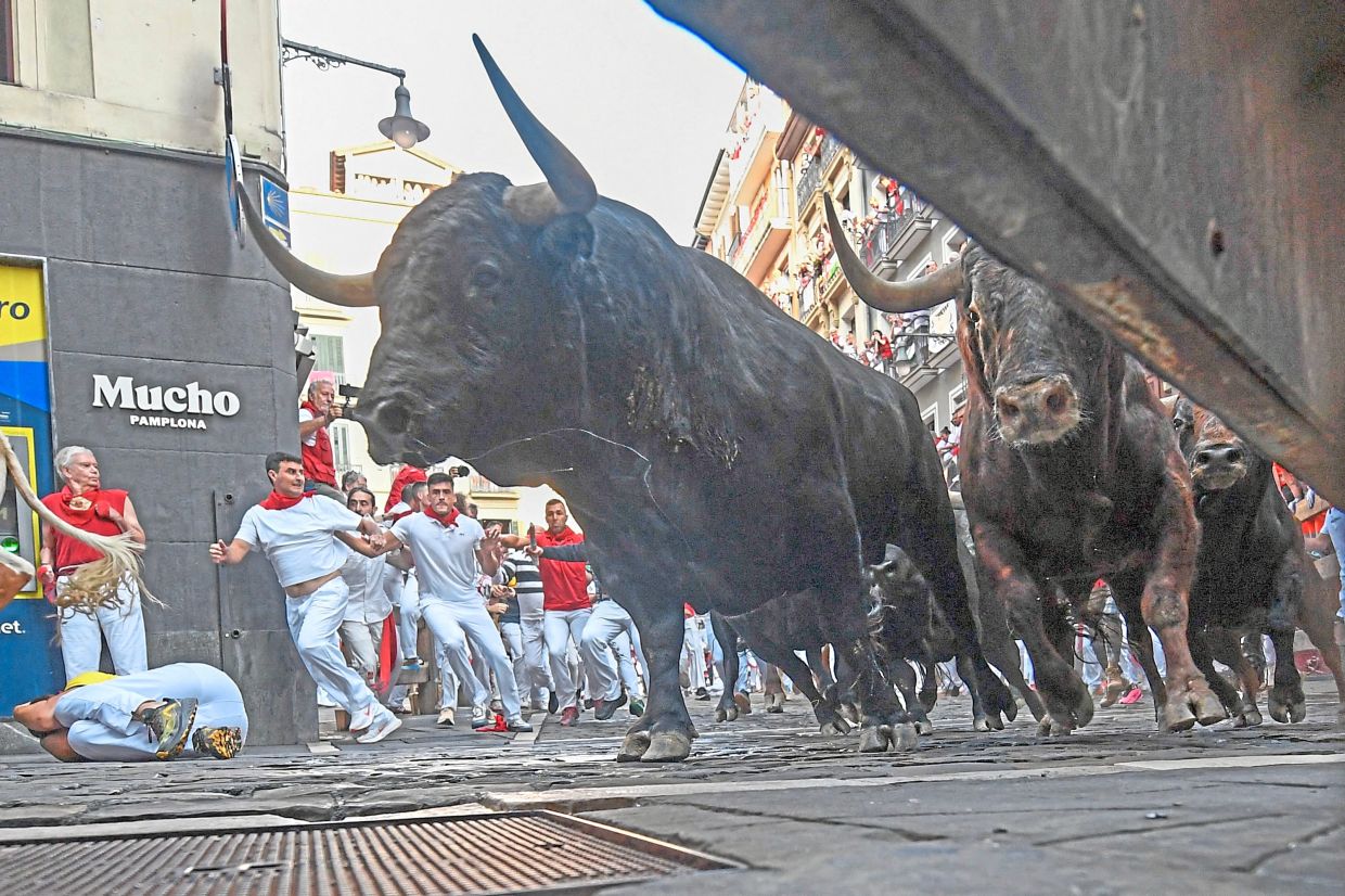 4. Bulls from the Victoriano del Río ranch thunder through the Mercaderes curve during the third running of the bulls. The highlight of the festival is the early morning bull runs, when thousands of runners sprint to avoid six bulls charging along a winding cobblestoned route to the city’s bullring. — AFP