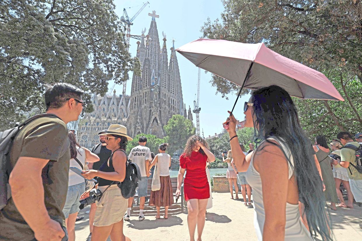 4. A woman shielding herself from the sun with an umbrella while visiting La Sagrada Família during a heatwave in Barcelona, Spain. The country’s weather agency issued its highest-level red heat alert in three eastern regions, with temperatures forecast to soar above 40°C. — AFP