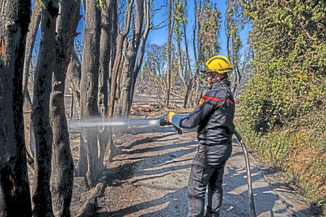 3. A firefighter spraying water on smoke plumes to stop a wildfire from reigniting in Ille-sur-Tet, southern France. Hundreds of firefighters, supported by specialised aircraft, fought to contain a ‘gigantic’ blaze in the Pyrenees-Orientales region, forcing the evacuation of more than 10,000 residents near Perpignan. — AFP