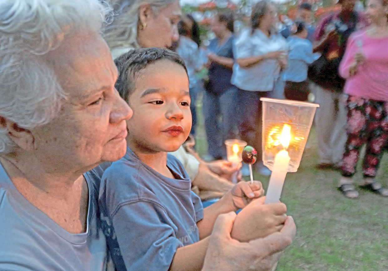 9. A woman and child hold candles during a vigil for earthquake victims in Valencia. — Reuters