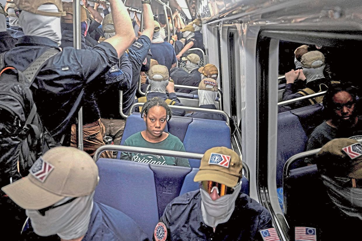7. A commuter sitting quietly as members of the Patriot Front ride the Metro on the 250th anniversary of US Independence in Washington, DC.