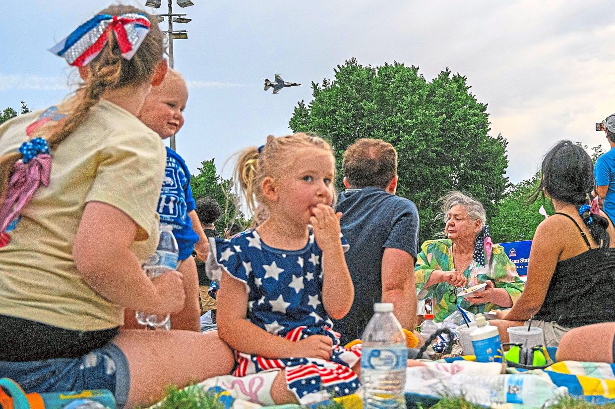 9. Perched beside her parents, a young girl looks on as the Thunderbirds streak across the skies above the Great American State Fair on the National Mall in Washington, DC.
