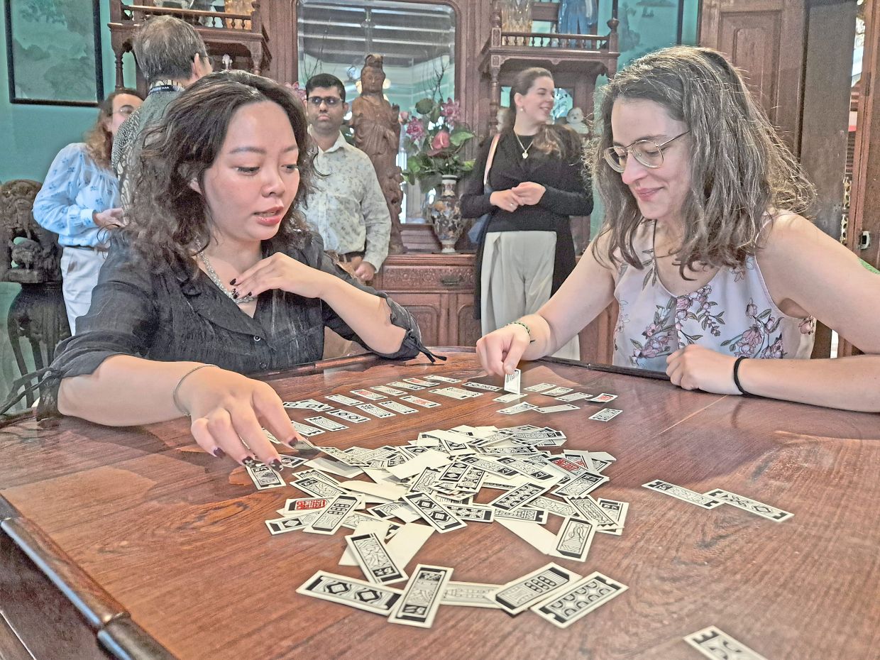 Diplomatic Academy of Vietnam’s Kim Giang Do (left) and Prague Office of the Central European Institute of Asian Studies research fellow Veronika Blablova try their hand at the traditional Peranakan card game, Cherki, during their visit to the Peranakan Museum.