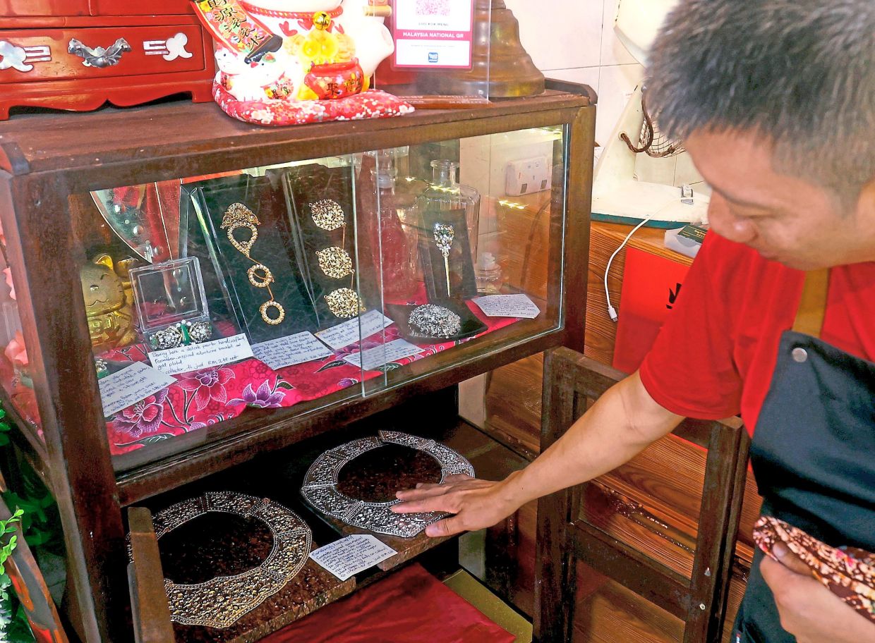 Chai pointing out to some of the prized Peranakan accessories on display, which include brooches, bracelets and necklaces.
