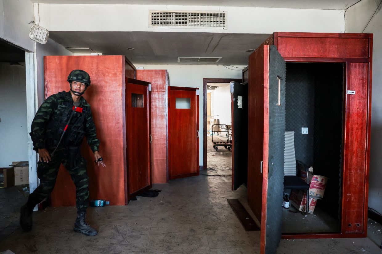 A Thai soldier walking near small booths lined with acoustic foam used to make scam calls to victims, inside a compound in the O’Smach area. - Reuters