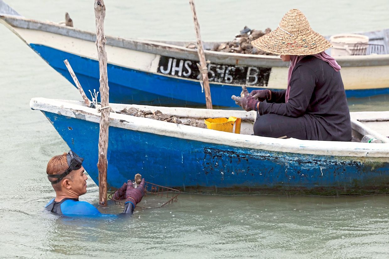 Divers place a long wooden pole into the riverbed next to the boat to guide them in the dive to the bottom.