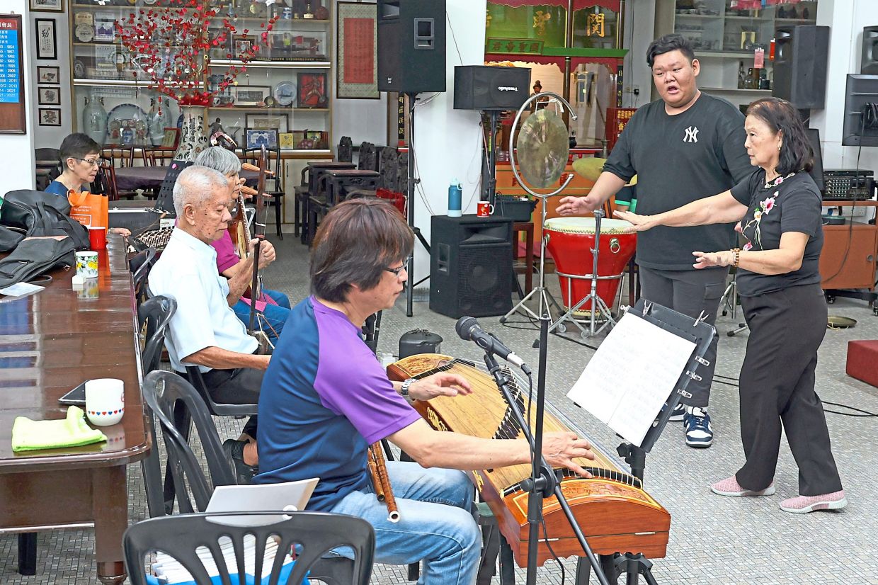 (From right) Loke and 15-year-old Zhi Hua at a Cantonese opera singing practice with musicians at Perak Shun Tak Association in Ipoh.
