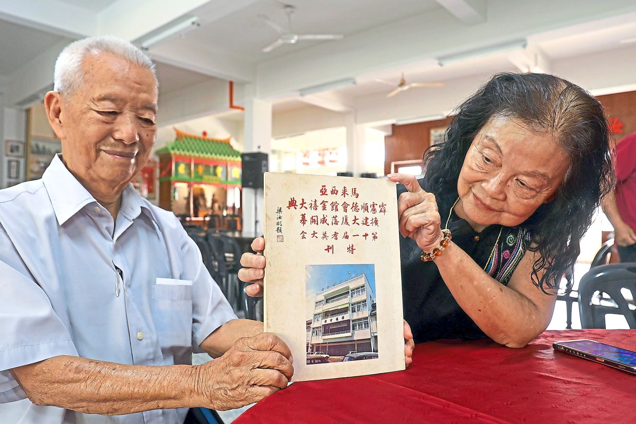 Lau (left) and Loke showing a book on the history of Perak Shun Tak Association.