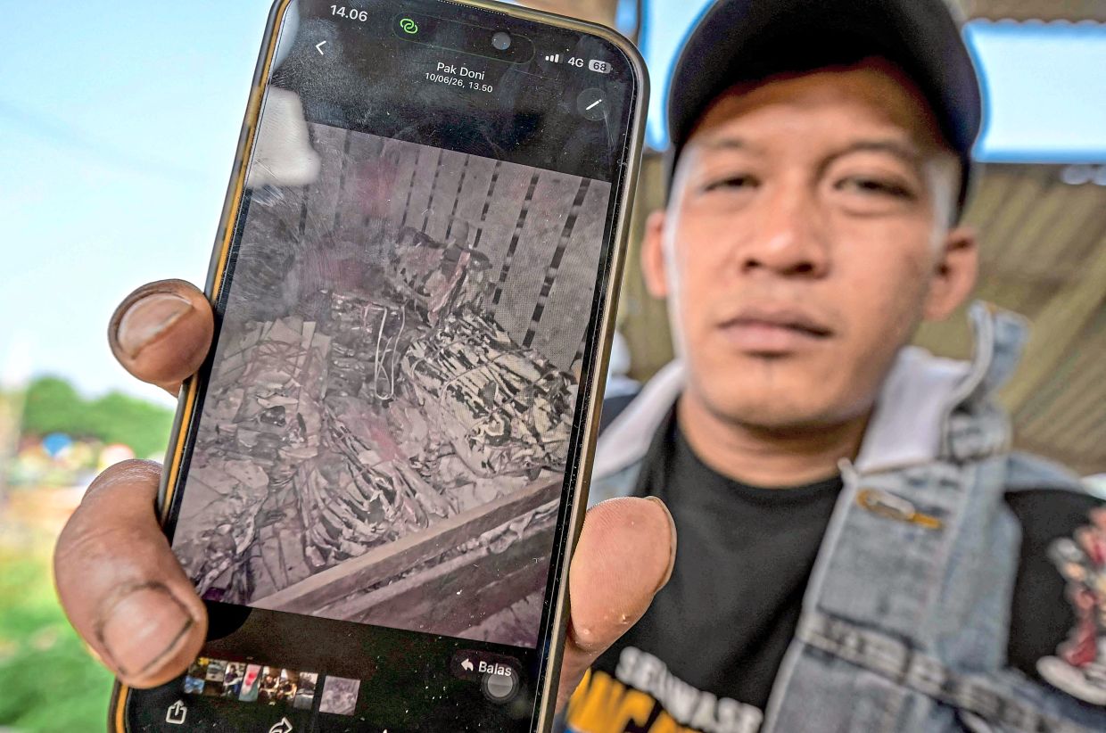 Jamaludin showing a photo displaying shark fins during an interview. — AFP