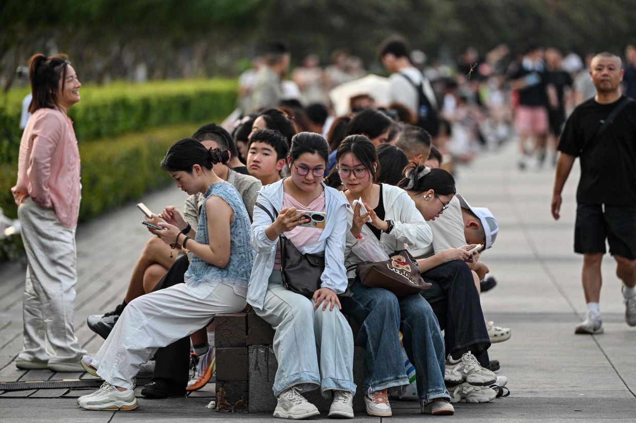 People visit the Bund promenade along the Huangpu river in Shanghai on Friday, July 17, 2026. -- Photo by Hector RETAMAL / AFP