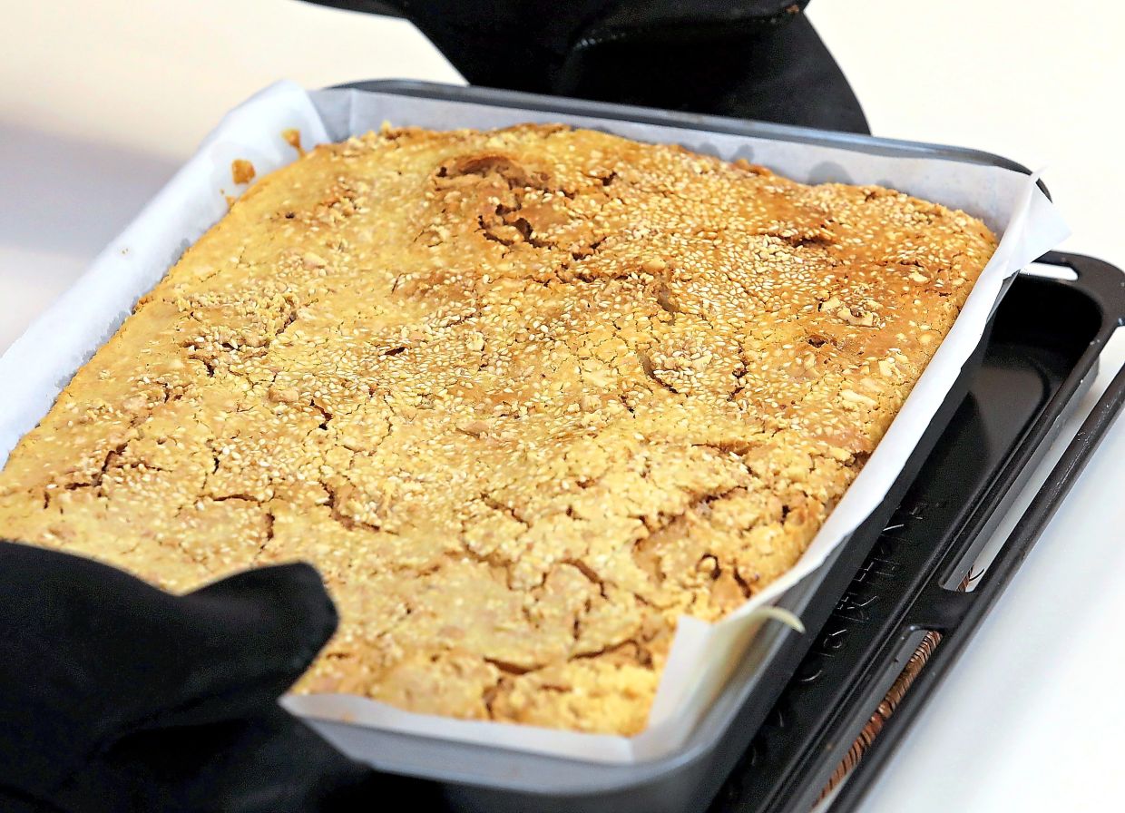 A 55-minute bake, or until a skewer comes out clean, results in a cake with peanut butter filling and crunchy topping of roasted peanuts and toasted sesame seeds.