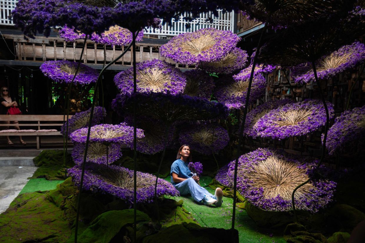 A woman poses for a photo at a display point during the RakDok Floral Weeks exhibition in Bangkok on Saturday, July 18, 2026. -- Photo by Candida NG / AFP
