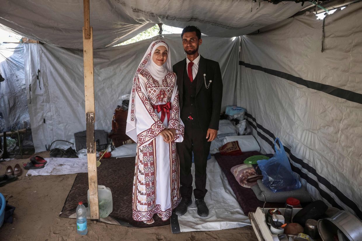 A Palestinian bride and groom pose for a photograph in their wedding outfits inside a tent after their wedding ceremony in Khan Yunis, in the southern Gaza Strip in early July. Photo: AFP