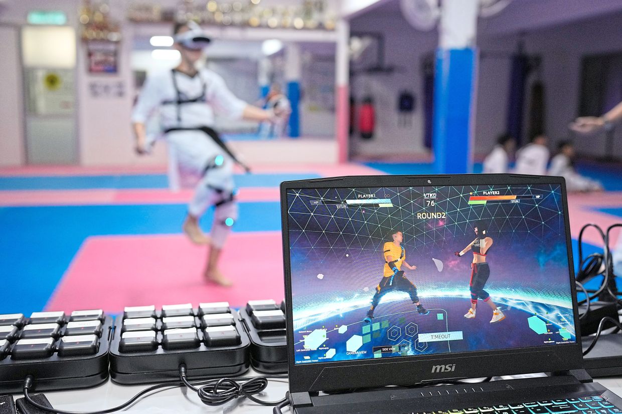 A laptop displays a virtual taekwondo match as a practitioner trains.