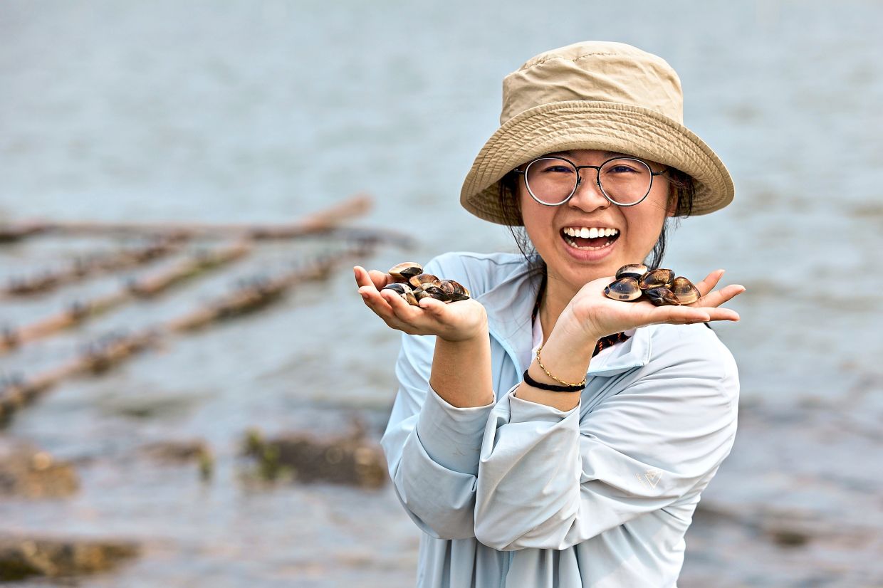 A visitor poses with the clams harvested at Haomei Boat Houses in Haomei, Budai Township, Chiayi, Taiwan.