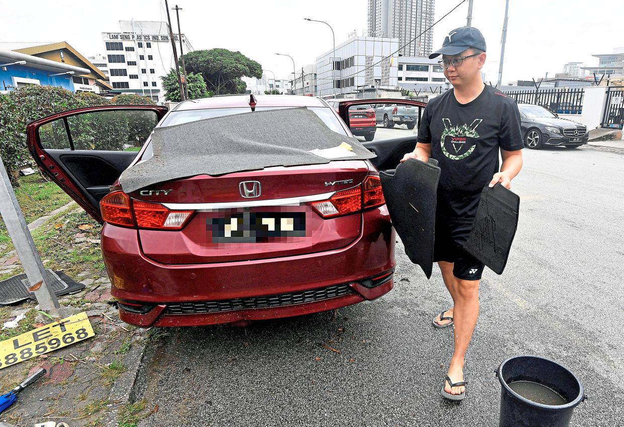 Ng clearing his flood-damaged car while waiting for tow truck to arrive.