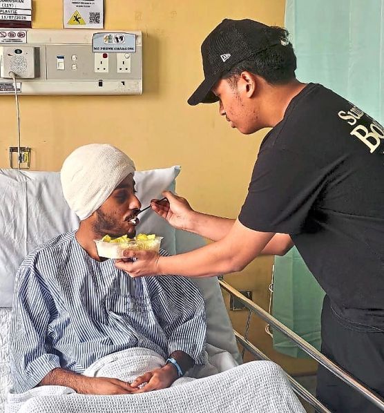 Helping hand: Maanroshan being fed by his friend Mohamed Eiman Rayyan Mohd Alfian during a visit at Hospital Putrajaya. — Courtesy of Charanjeet Kaur