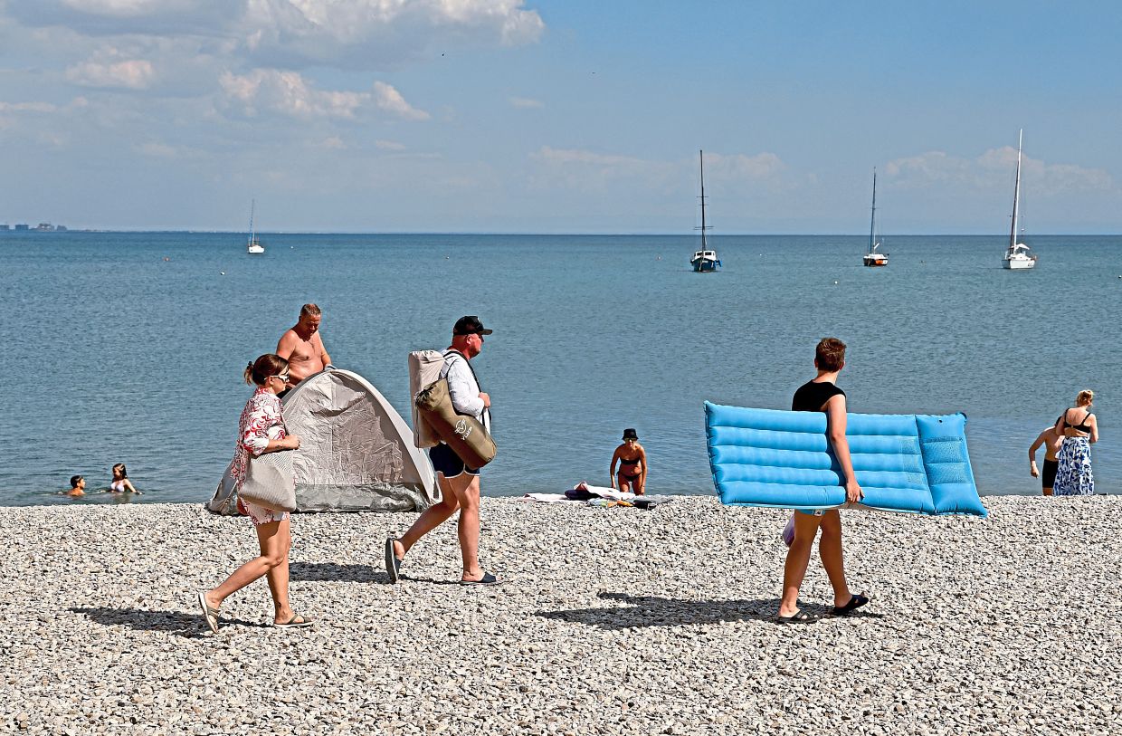 Tourists and locals walking and chilling out on the beach in the resort city of Yevpatoriya in Crimea.