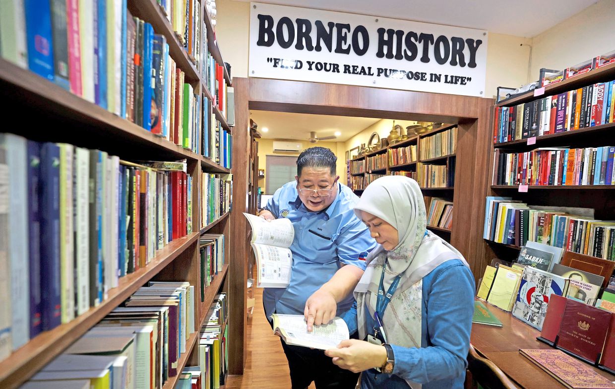 Shari (left) explains the collection and history of Sabah’s stamps at his home in Kota Kinabalu recently. Photo: Bernama