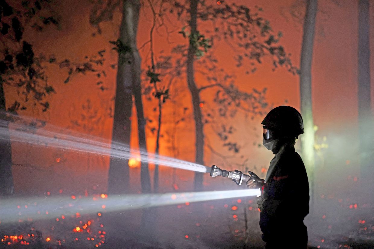 A firefighter spraying water to extinguish flames in the Fontainebleau forest. — Photo: Reuters