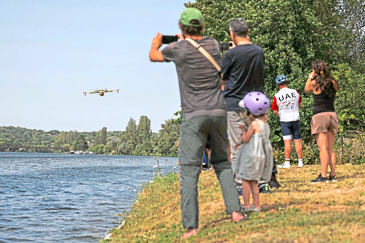 Local residents taking pictures of the Canadair CL-415 firefighting aircraft. — AFP