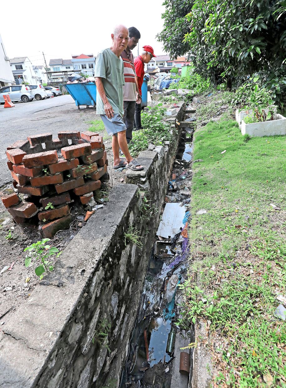 Residents at Flat Taming Jaya Kiri in Balakong, Selangor, looking at a heavily littered drain inside their residential compound.