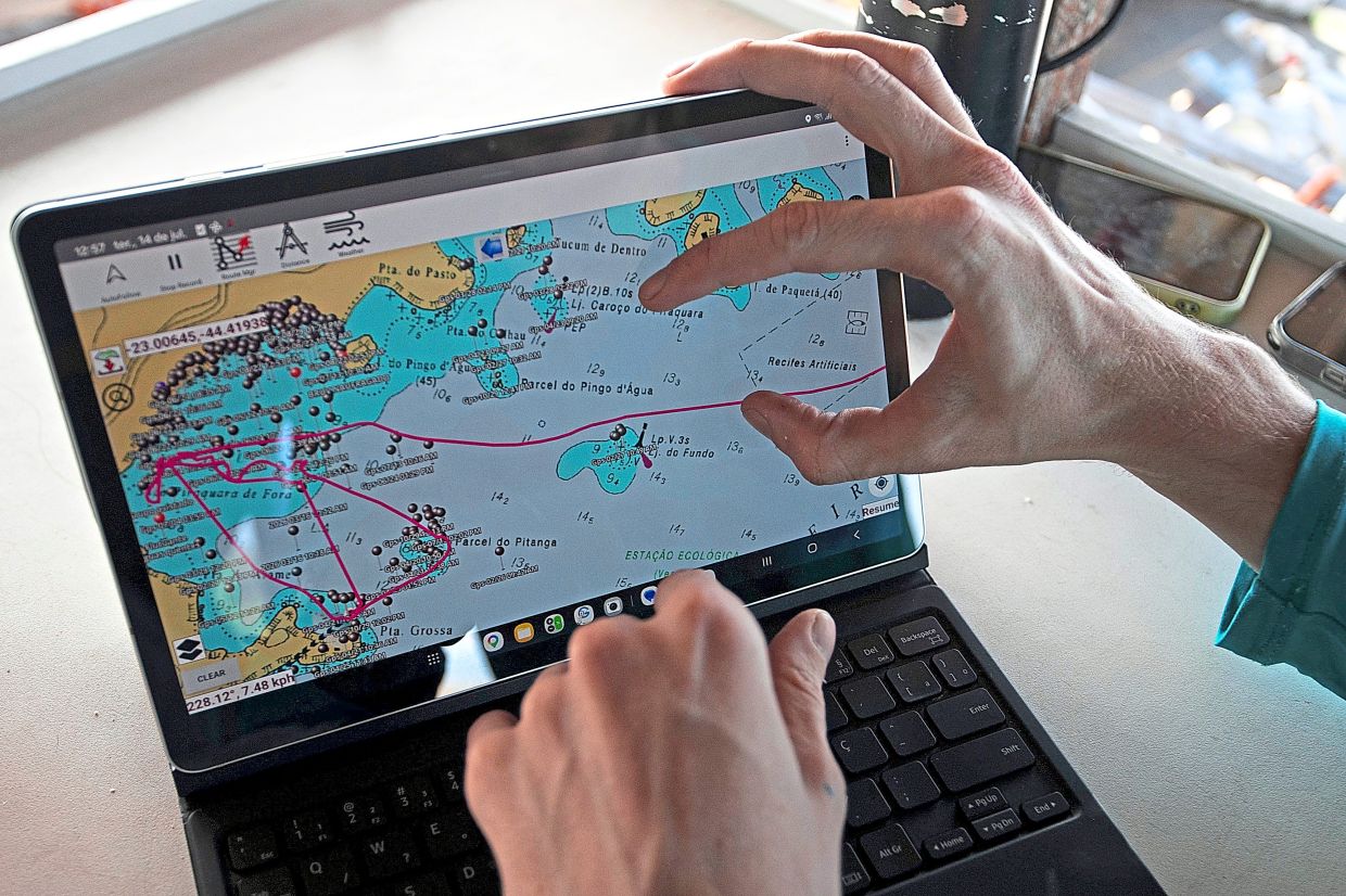 A researcher displays a tablet with a mapping system used to identify research sites for a shark project in Ilha Grande Bay, Angra dos Reis, Rio de Janeiro state, Brazil, July 14, 2026. (AP Photo/Bruna Prado)