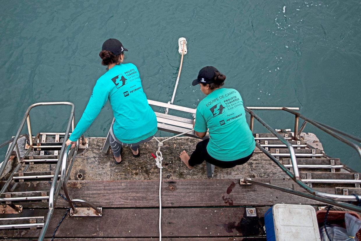 Researchers Beatriz da Costa e Castro, left, and Thaissa Albuquerque Ribeiro Augusto deploy a Baited Remote Underwater Video System as part of a shark project in Ilha Grande bay.