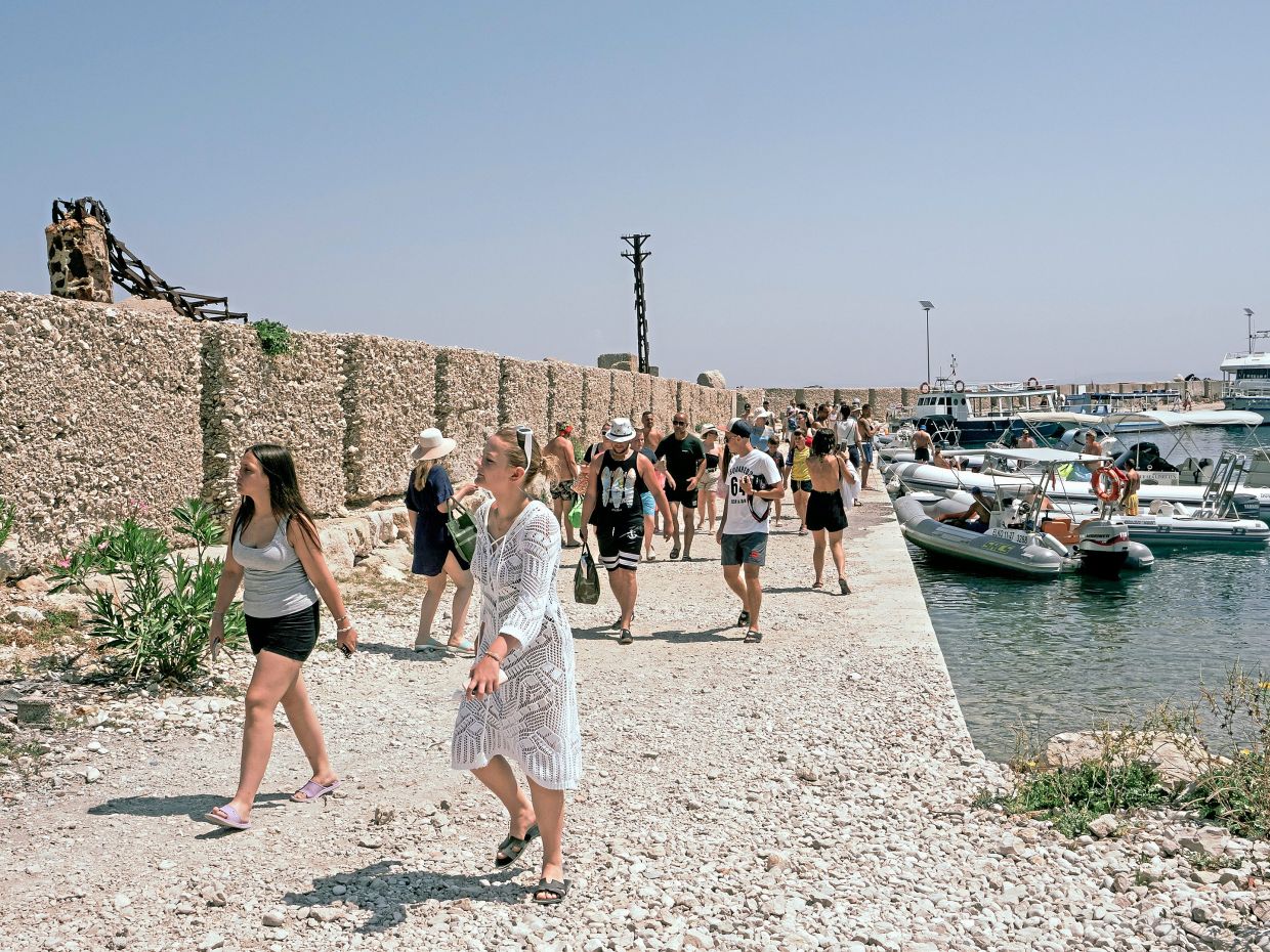 Holidaymakers at a pebble beach on Sazan Island, which is coveted by Trump and Kushner for a luxury hotel and resort development. — Ilir Tsouko/The New York Times