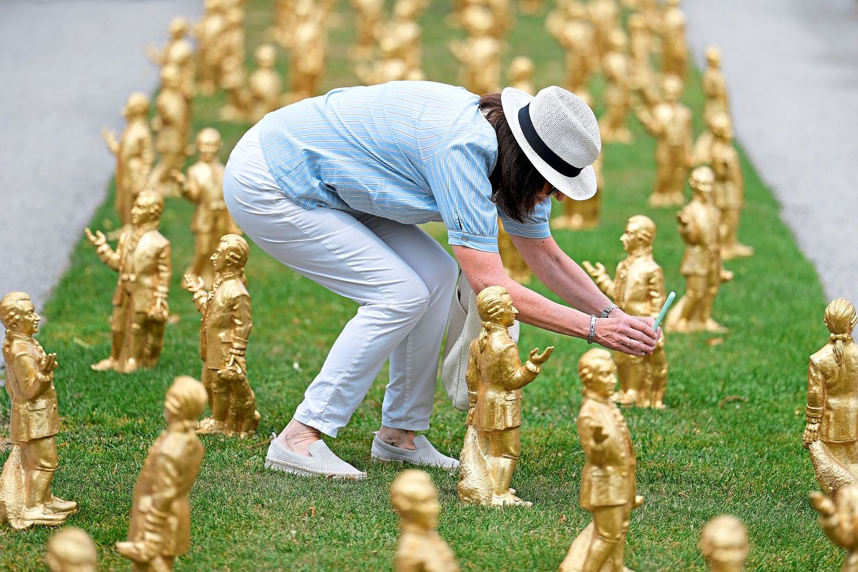 A woman takes pictures of the gold coloured plastic Mozart sculptures. Photo: AP
